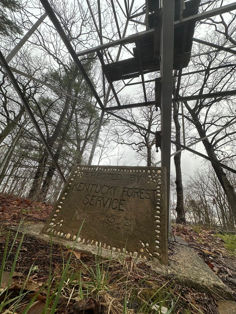 Low-angle view of the tower’s base with a plaque reading “Erected by Kentucky Forest Service, May 1939.