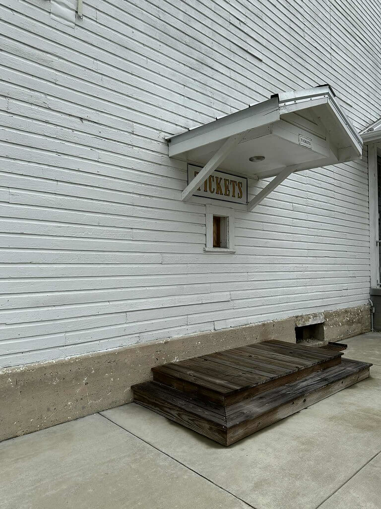 Old ticket window and wooden steps along the white clapboard exterior of the historic Wayland gym in Wayland, Kentucky.