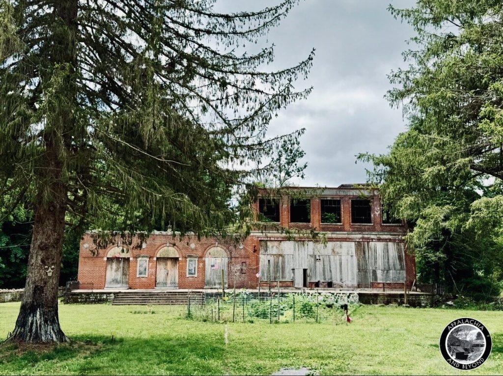 Abandoned 1917 Pocahontas Fuel Company store in Boissevain, Virginia, two-story brick with boarded windows, overgrown lawn.