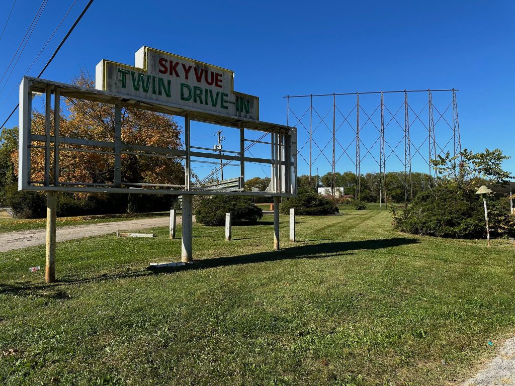 Weathered “Skyvue Twin Drive-In” marquee beside the road, with the empty steel screen frame in the background.