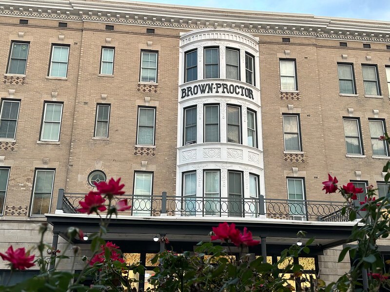 Front view of the Brown Proctor Hotel in downtown Winchester, Kentucky, with red roses in the foreground.