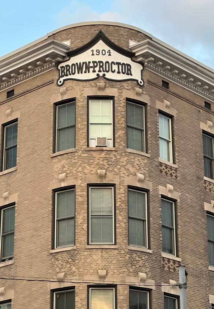 Close-up of the Brown Proctor Hotel’s 1904 corner façade in Winchester, Kentucky, showing arched windows and decorative cornice.