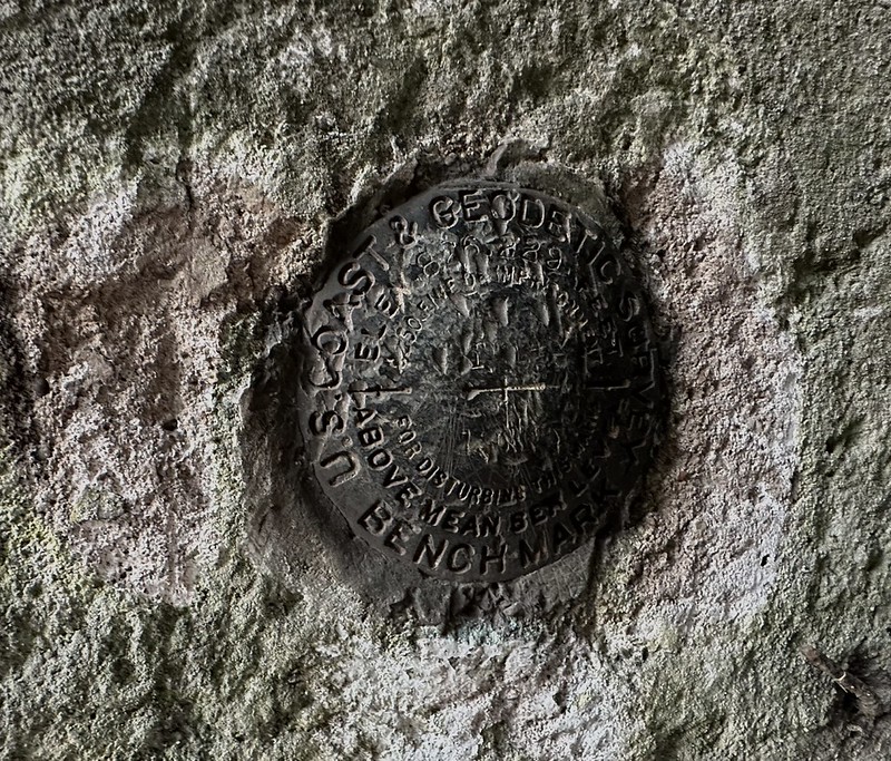 Close-up of a weathered U.S. Coast & Geodetic Survey benchmark disk embedded in rough rock inside the Yerkes tunnel area in Perry County, Kentucky.