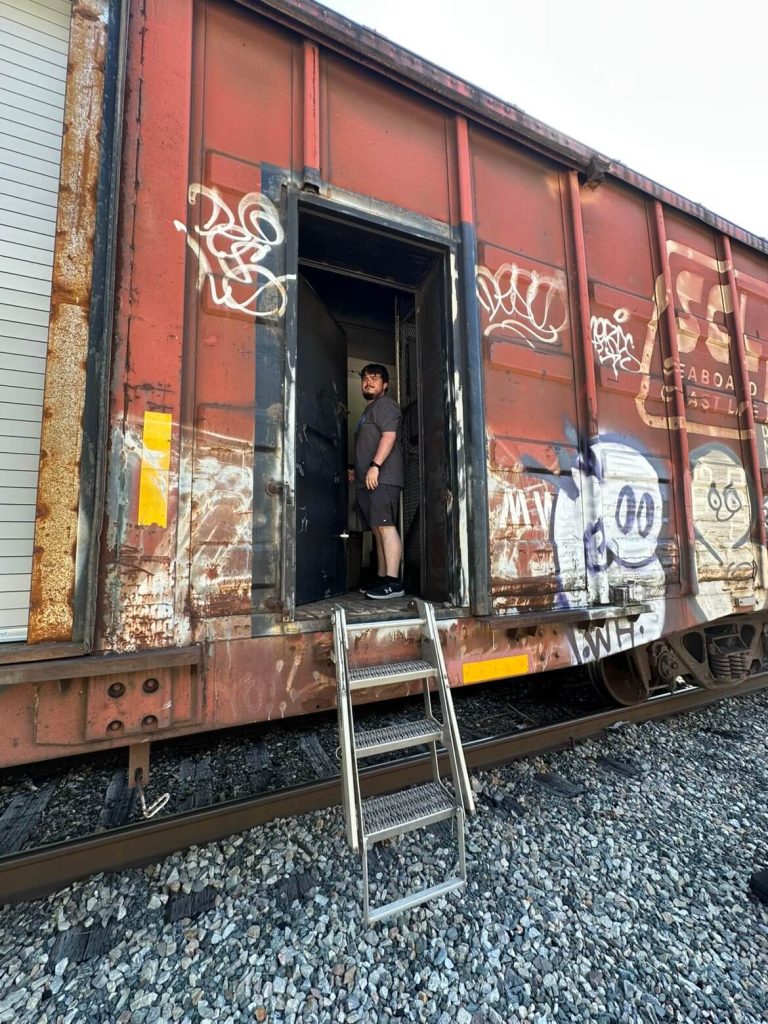 Picture of Alex Hall standing in a train.